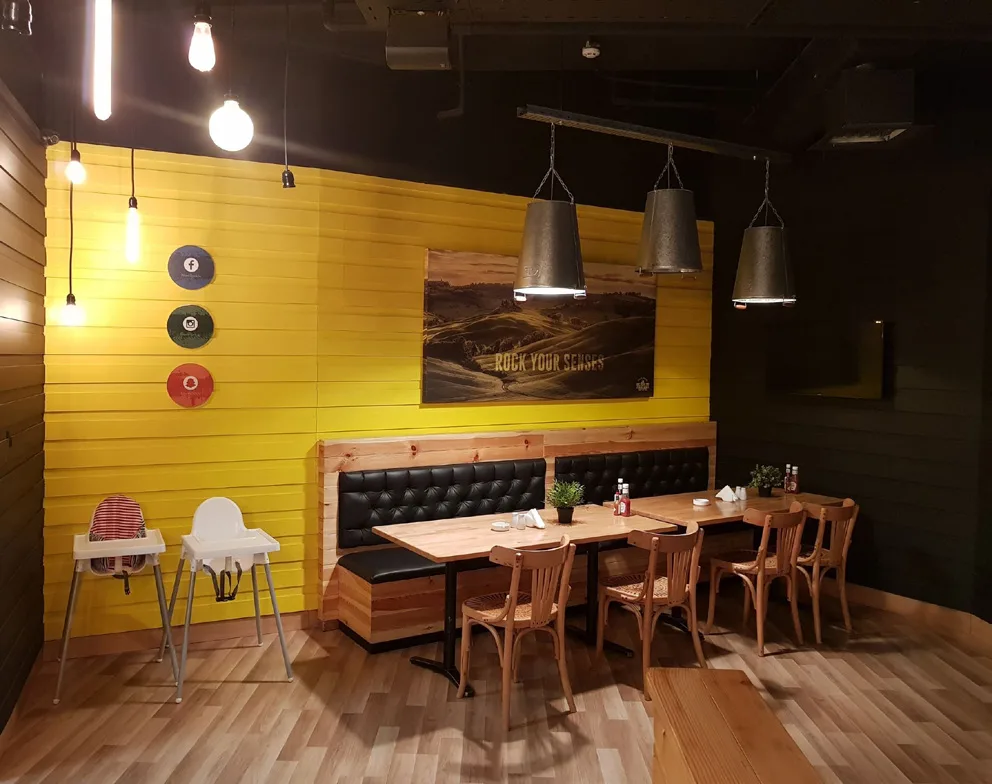 Black Rock Steakhouse timber tables and tufted banquette against a yellow wall