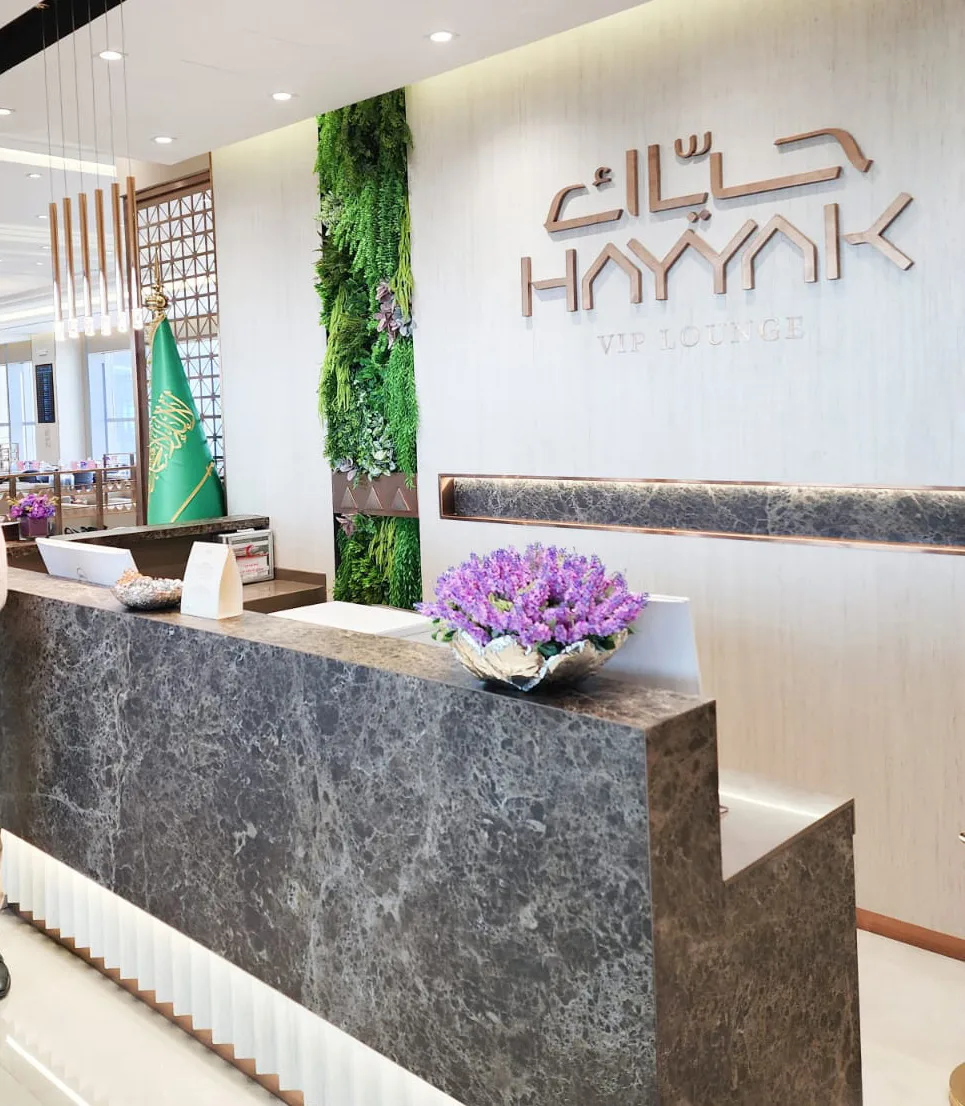 Hayyak Lounge T5 stone reception desk beneath the wall logo