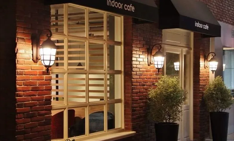 Indoor Café brick facade at night with lanterns and white window shutters