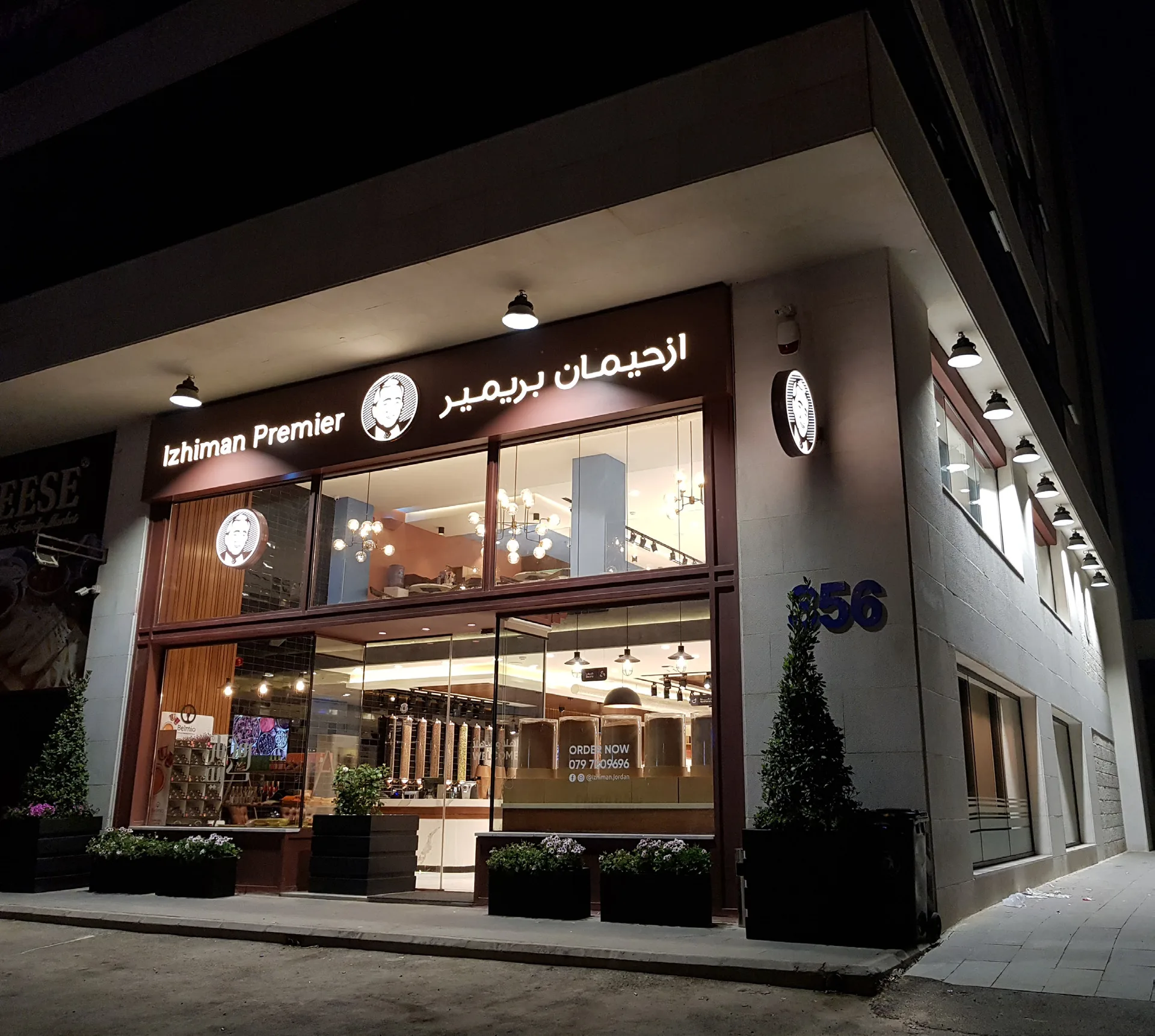 Izhiman Premier corner storefront at night with illuminated signs and large display windows