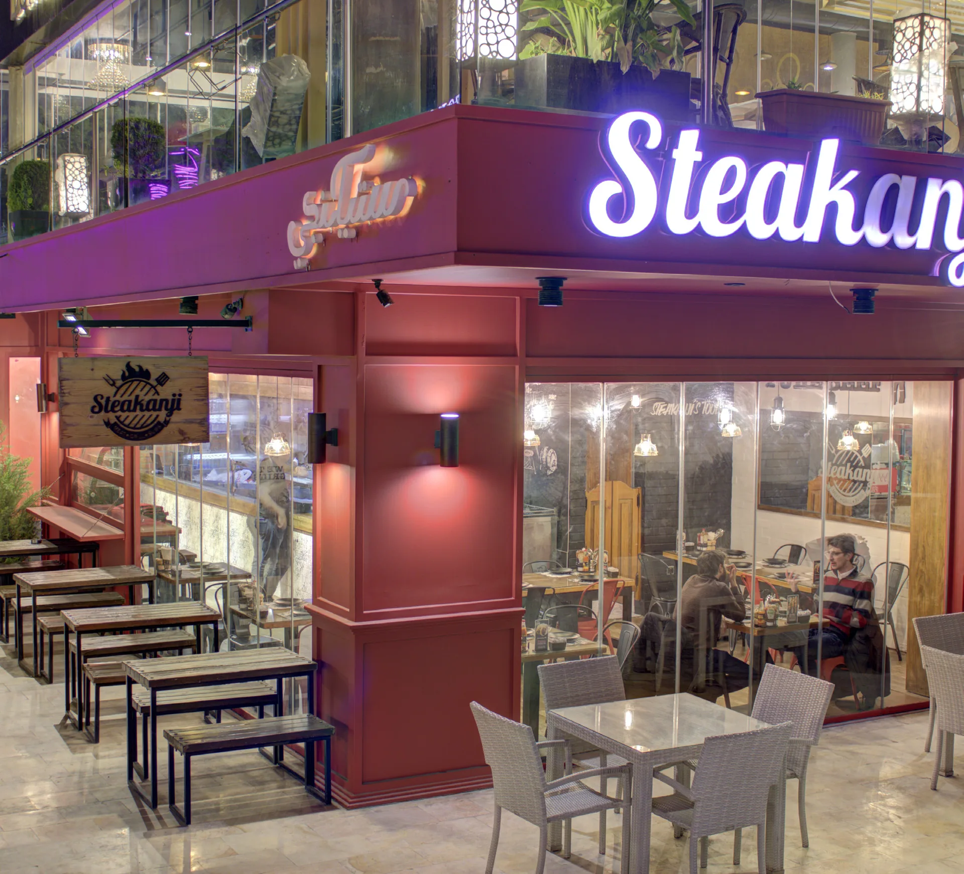 Steakanji corner entrance with burgundy signage and pavement seating