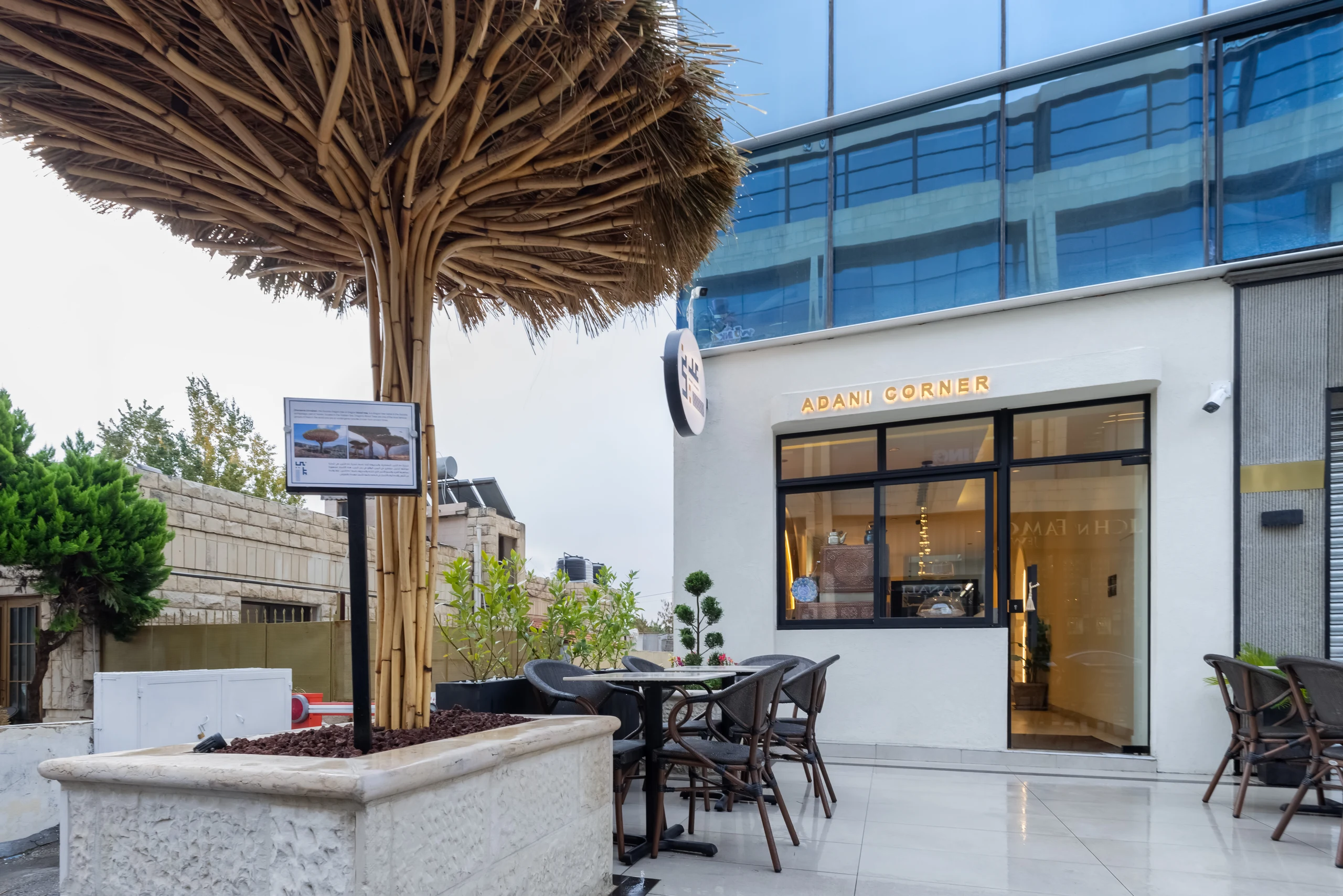Adani Corner café entrance and outdoor seating beneath a sculptural woven canopy in Amman